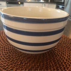 a white and blue striped bowl sitting on top of a woven place mat in a kitchen