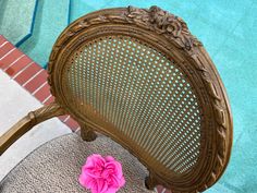 a pink flower sitting on top of a wooden chair next to a swimming pool in the background