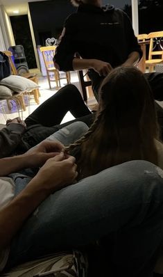 two people sitting on a couch with one person petting the dog's tail