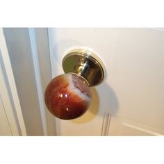 a door knob with a marbled red ball on it's side and a white wall in the background