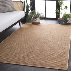 a living room area with a couch, potted plants and a rug on the floor