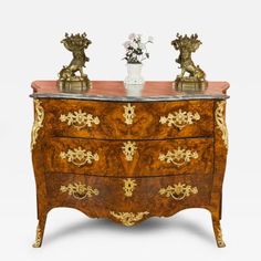 an ornately decorated chest of drawers with two vases on top