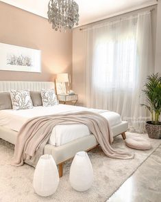 a bedroom with a large bed, chandelier and two white vases on the floor