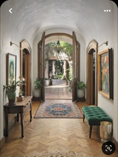 a hallway with an arched doorway and wooden flooring is shown in this image, there are two green benches on either side of the entryway