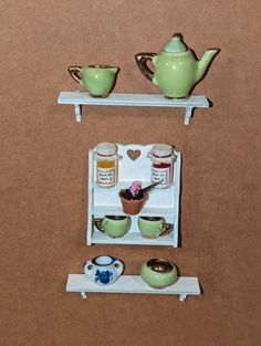 there is a miniature shelf with tea pots and cups on it in the shape of a refrigerator