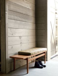 a bench sitting in front of a wooden wall next to a door with a window