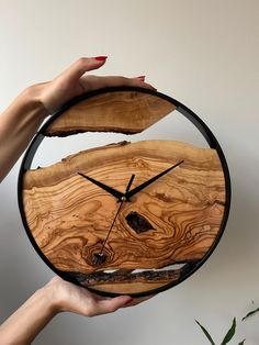 a person holding a wooden clock in their hand