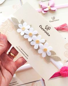 a person is holding up a card with flowers on it and two other items in the background