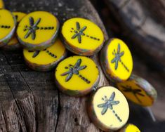 some yellow and black dragonfly buttons on a piece of wood