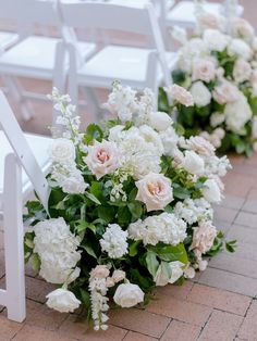 white flowers and greenery are lined up along the aisle