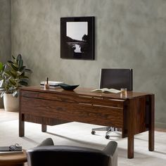 an office desk with a laptop on it in a living room next to a potted plant