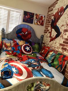 a bedroom with a bed covered in spiderman sheets and pillowcases, along with pictures on the wall