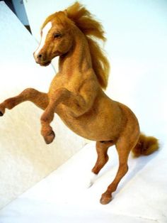 a brown horse standing on its hind legs in front of a white wall and looking at the camera