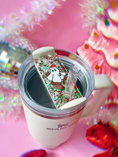 a coffee cup with a sticker on the lid sitting next to some candy canes