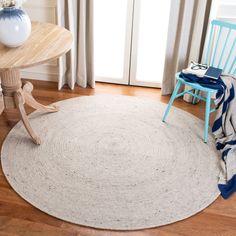 a chair and table in a room with wooden floors, white rugs and curtains