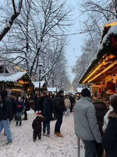 people are walking around in the snow at an outdoor christmas market on a snowy day