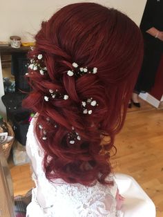 a woman with red hair and white flowers in her hair is seen from the back