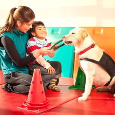 a woman and child petting a dog in front of a cone on the floor