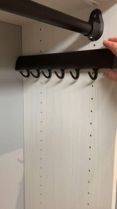 a hand is holding a black rack with hooks on it