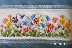 a cross stitched pillow with flowers on it