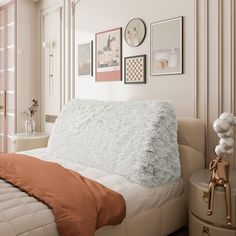 a white bed sitting next to a window with pictures on the wall above it in a bedroom