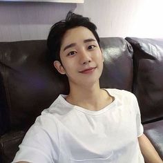 a young man sitting on top of a brown couch