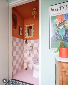 an open door leading to a bathroom with pink and white tiles on the walls,