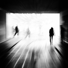 black and white photograph of people walking through a tunnel