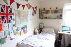 a bedroom with a bed, desk and various pictures on the wall above it's headboard