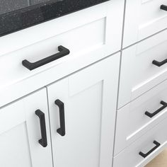 a kitchen with white cabinets and black counter tops