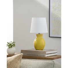 a yellow vase sitting on top of a stack of books next to a white lamp