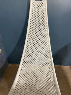 a white wicker chair sitting on top of a tile floor next to a blue wall