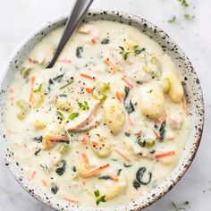 a white bowl filled with chicken and dumplings on top of a marble countertop