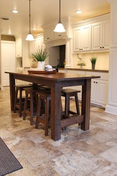 a kitchen with white cabinets and an island table surrounded by stools in the center