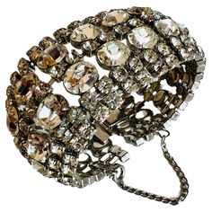 Opulent vintage bracelet, spanning seven rows wide and embellished with clear rhinestones, including both round and sizable oval cuts, all elegantly mounted in silver tone prong settings and enhanced with a safety chain for added security. Ideal for achieving a Hollywood Regency glamour aesthetic or for a bride seeking sophisticated elegance. Size: 7" long x 1-1/2" wide. Weight: 65.1 grams. Markings: Unmarked. Condition: Very good condition. Well-constructed. No missing rhinestones. Glamour Aesthetic, Glamour Vintage, Vintage Glam, Safety Chain, Vintage Bracelet, Rhinestone Bracelet, Hollywood Regency, Vintage Bracelets, Clear Rhinestones