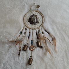 a dream catcher with feathers and beads hanging from it's side on a bed