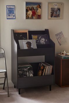 there is a book shelf in the corner of this room with pictures on the wall