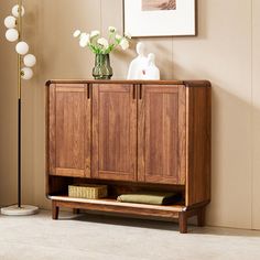 a wooden cabinet sitting next to a vase with flowers