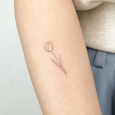 a woman's arm with a single flower tattoo on the back of her left arm