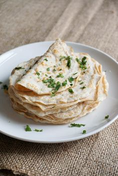 a stack of flatbreads on a plate with parsley sprinkled on top