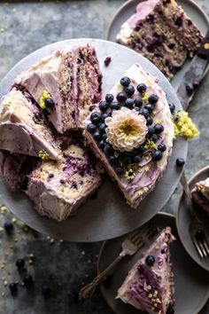 a piece of cake on a plate with blueberries and other dessert items around it