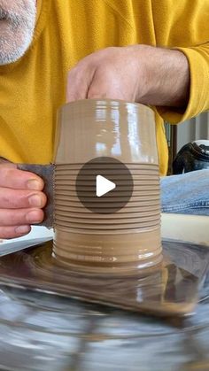 a man is making a vase out of clay with his hands on the top and bottom