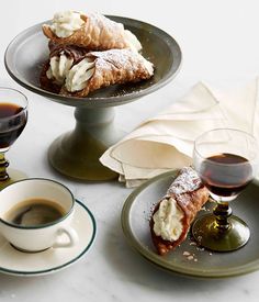 two plates with pastries on them next to cups and saucers