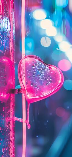 a heart shaped object with water droplets on it's side and lights in the background