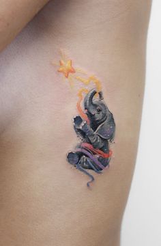 an elephant tattoo on the side of a woman's stomach is painted with watercolors