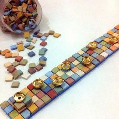 there are many different colored buttons on this mosaic tile pattern that has been made into a bracelet