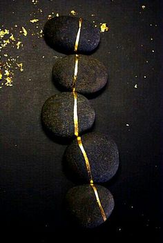 three black rocks with yellow string wrapped around them