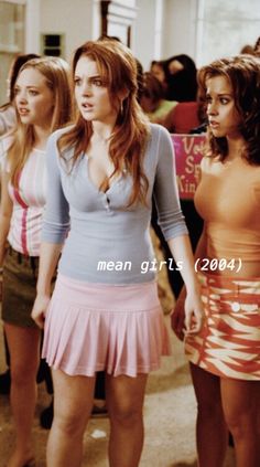 the mean girls are walking down the hallway in their dresses and skirts, one girl is pointing at something