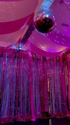 a disco ball hanging from the ceiling in front of purple curtained walls and drapes