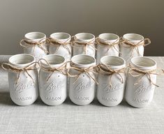 six mason jars tied together with twine and burlocks are sitting on a table